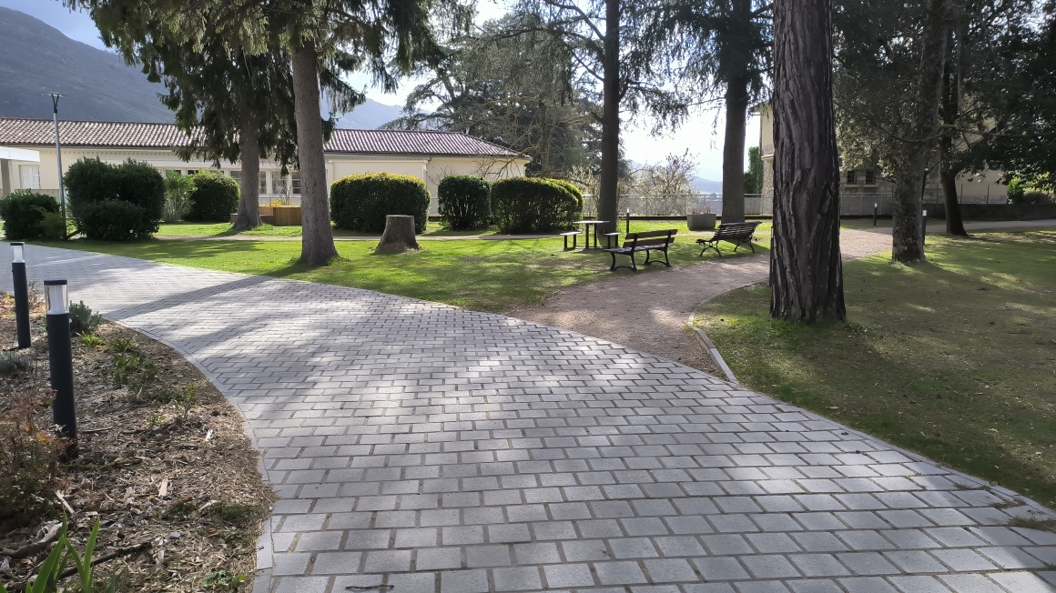 Allée pavée sereine avec bancs sous les arbres, aménagée par jardins-paysages en Ariège