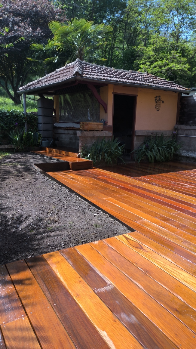 Terrasse en bois brillante dans un jardin paysager avec cabane en fond par jardins-paysages en ariège